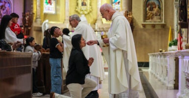 Boston, MA - April 23: Rev. James Wallace, C.Ss.R., distributes communion to a parishioner during afternoon Mass at the Basilica of Our Lady of Perpetual Help on April 23, 2025. The Redemptorists have ministered to this parish since its founding in 1870, serving a congregation that now includes immigrants from Ethiopia, Nigeria, and Haiti Wikipedia alongside longtime members. Despite Catholic identification in Boston falling from nearly one-third of adults in 2014 to 24% in 2023-2024, the basilica remains committed to nurturing a strong, open, and inclusive congregation that reflects the city's changing demographics. (Photo by Erin Clark/The Boston Globe via Getty Images)