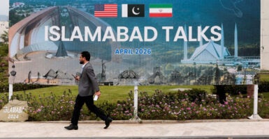 A man walks by a large sign reading 