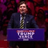 Tucker Carlson speaks from a Trump-Vance podium during 2024 campaign.