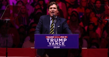 Tucker Carlson speaks from a Trump-Vance podium during 2024 campaign.