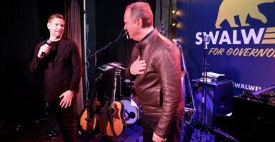 Eric Swalwell speaks to Adam Schiff on a small club stage in front of a 