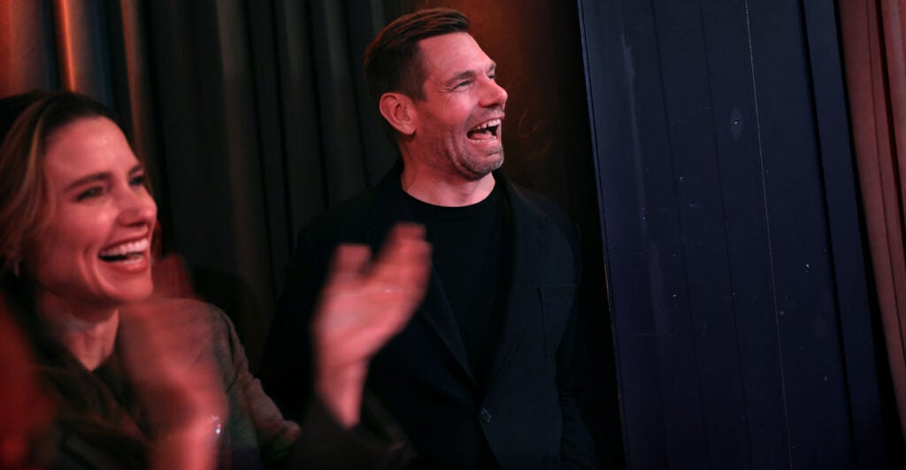 Eric Swalwell, in a black shirt, laughs alongside actress Sophia Bush.