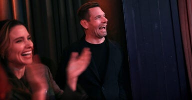 Eric Swalwell, in a black shirt, laughs alongside actress Sophia Bush.