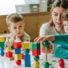 Female teacher helping little boy sort the cubes by color in a kindergarten