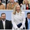 Abigail Spanberger standing and smiling in a white coat with other people seated nearby