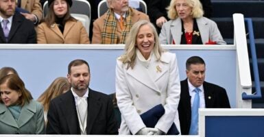 Abigail Spanberger standing and smiling in a white coat with other people seated nearby