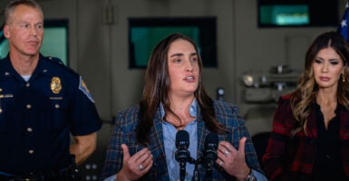Former Immigration and Customs Enforcement Deputy Director Madison Sheahan stands in the center of a podium at a press conference.