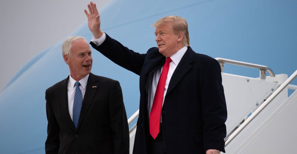 President Donald Trump waves while standing with Sen. Ron Johnson.