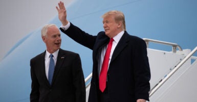President Donald Trump waves while standing with Sen. Ron Johnson.