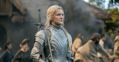Blonde woman Morfydd Clark in armor with a sword
