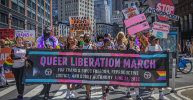 Protesters hold signs reading "Queer Liberation March"